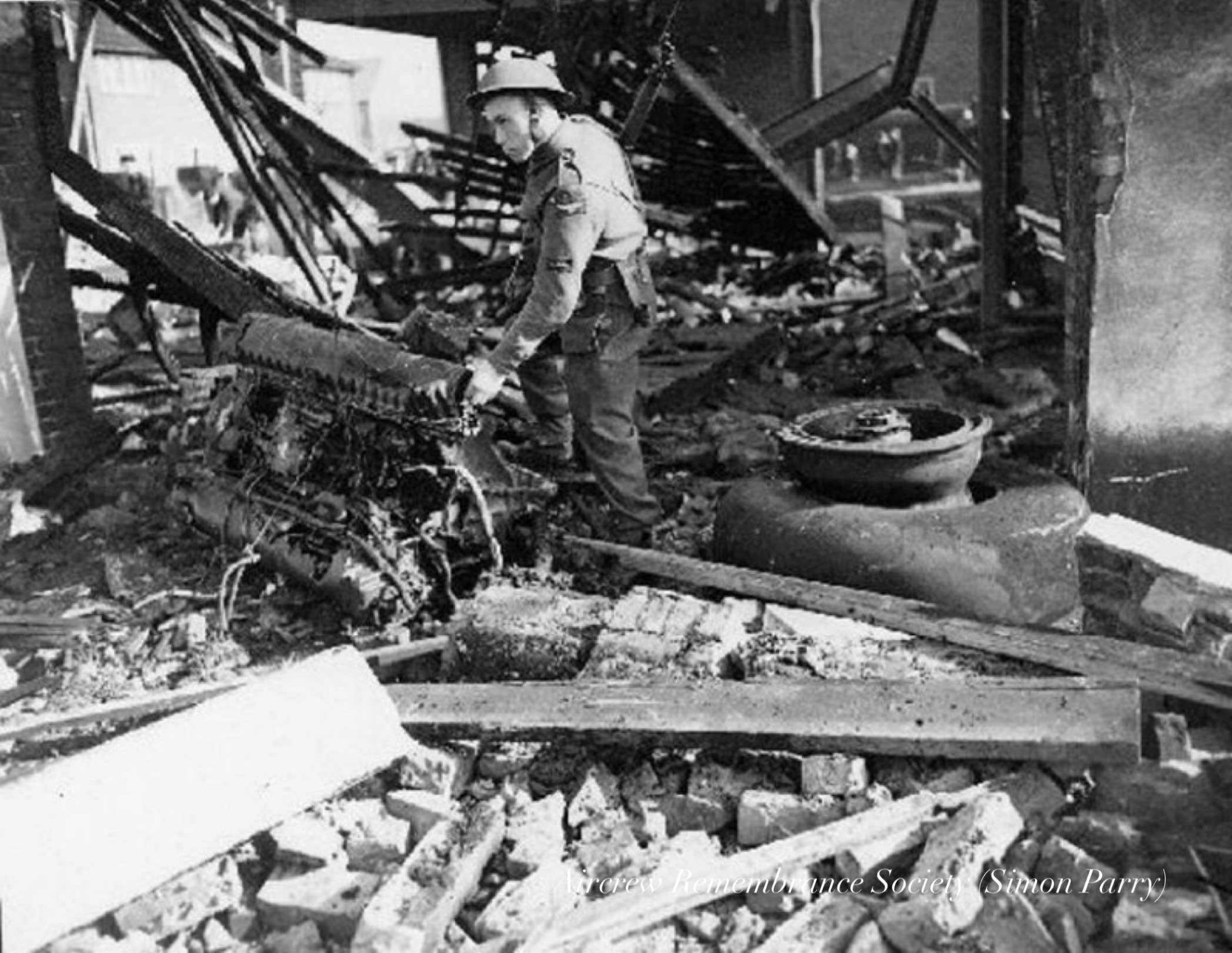 Aftermath of the crash, searching through the debris and aircraft wreckage One of the Junkers Jumo 211J-2 engines with main
wheel & tyre in the demolished building. (Parry)