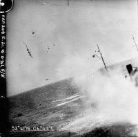 Blenheim V6034 tragically entering its death throes with debris from the ships mast and a section of the Blenheim’s outer starboard wing filling the air, the aircraft enters a high speed spin to starboard from which it would not recover, as large plumes of water engulf the ship with the explosions from its strike.
