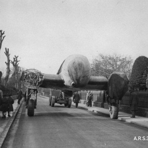 The aircraft now partly dismantled being transported down the street on its main wheels.