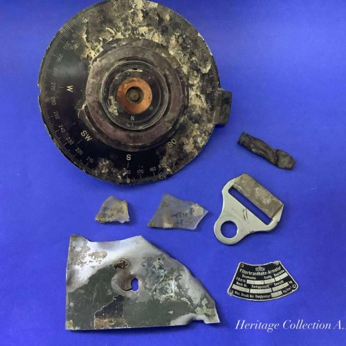 A collection of items held in the society’s Heritage Collection recovered from the crash site, navigation instrument, buckle, Label and other small parts.